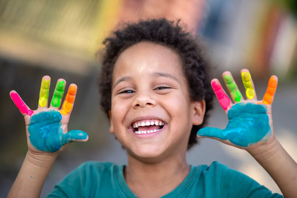 Smiling child raising brightly painted hands